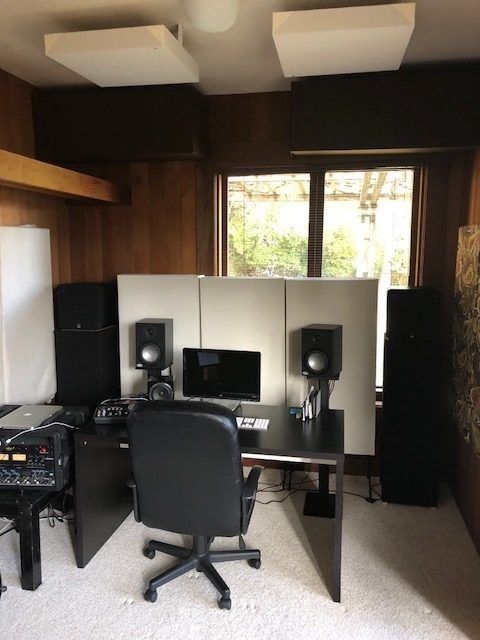 Hemmastudio med monitorhögtalare och akustikpaneler bakom skrivbordet
