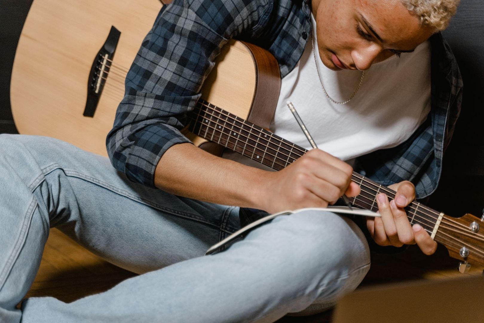 Person skriver med penna över en gitarr medan en annan gitarr ligger bredvid