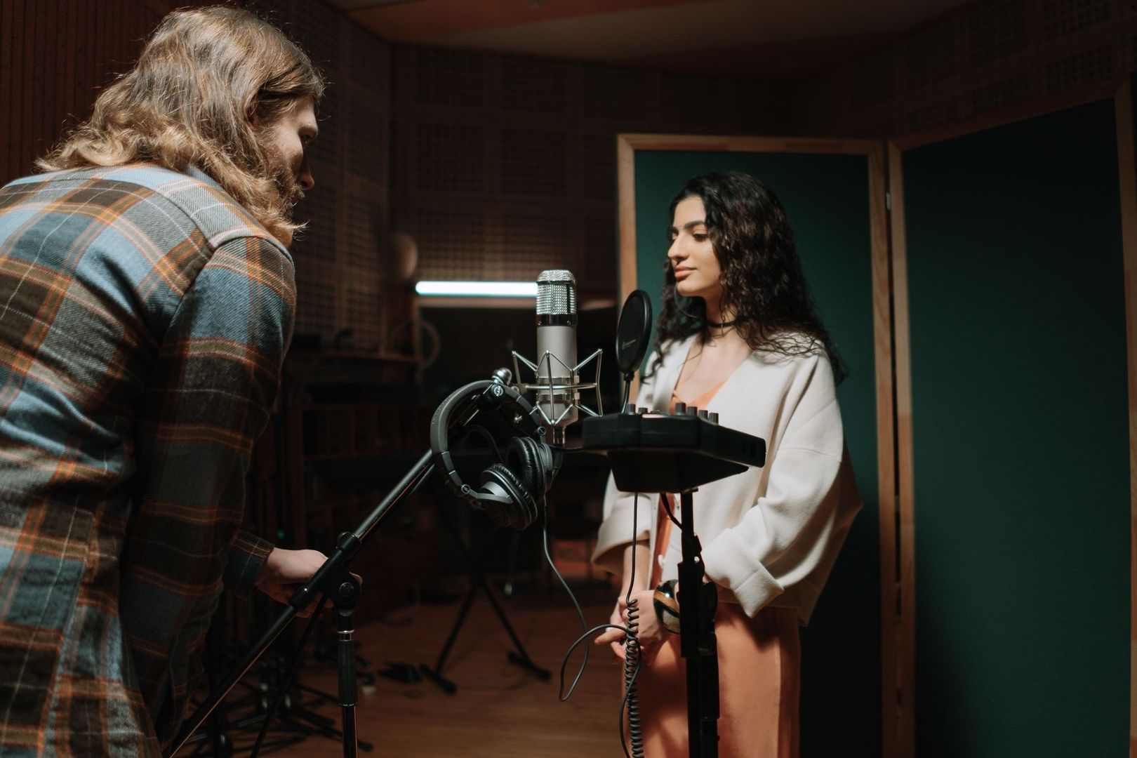 Två personer arbetar med inspelning vid en mikrofon i en musikstudio